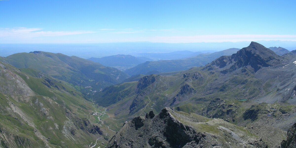 immagine dall'alto della Valle Po e della catena delle Alpi. tra i pascoli verdi si vedono le tracce dei sentieri