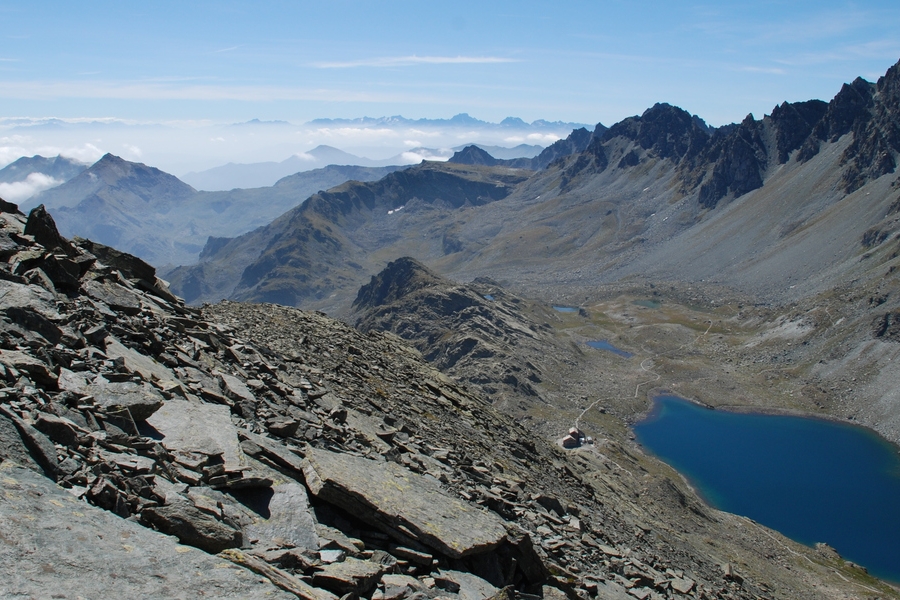 Panorama sull'alta valle Po: il lago Grande di Viso e il vicino rifugio Quintino Sella visti dal sentiero di salita al Viso Mozzo