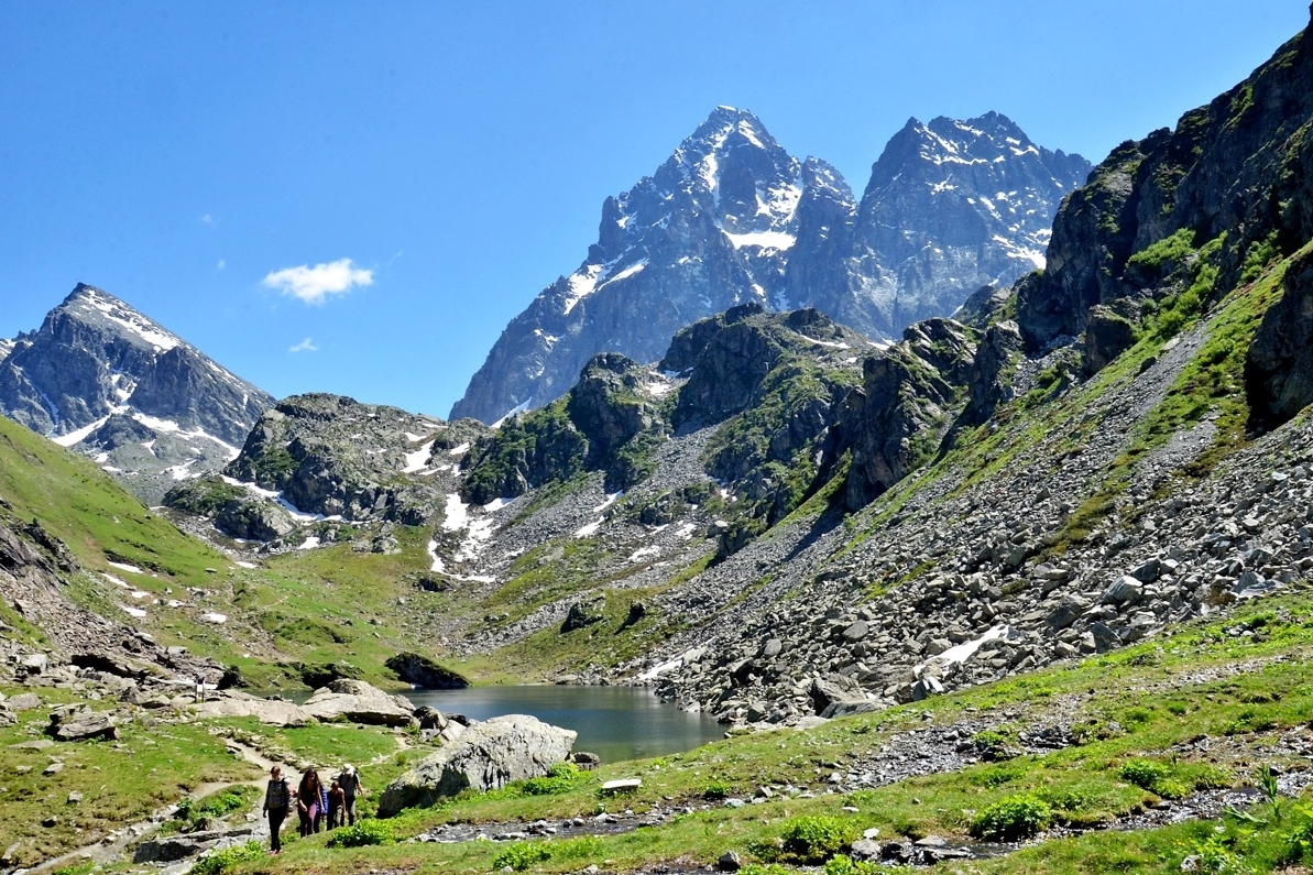 Il lago Fiorenza e il Monviso alle sue spalle, con un gruppo di escursionisti lungo il sentiero che corre lungo al lago