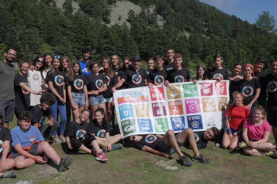 Foto di gruppo dei partecipanti alla prima edizione del MaB UNESCO Monviso Youth Camp: ragazzi ed educatori con un pannello che riporta i 17 Obiettivi di Sviluppo Sostenibile dell'Agenda 2030 nei pressi del lago Bagnour, in valle Varaita