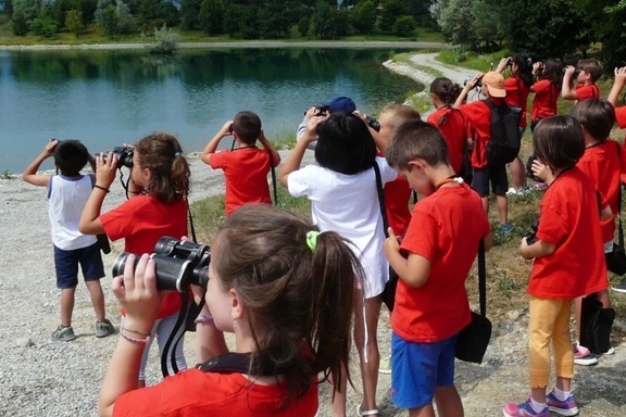 Bambini con un binocolo intenti ad osservare un tratto del fiume Po: un momento di una attività didattica
