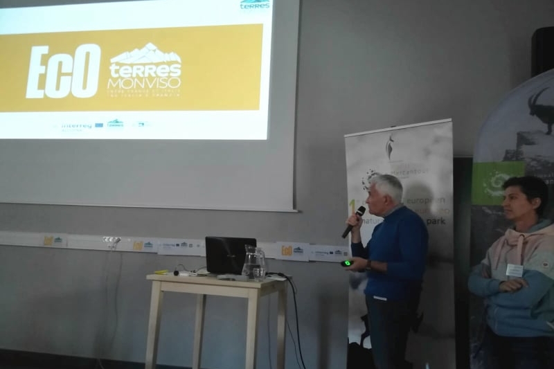 Maurilio Paseri, responsabile del Progetto EcO Terres Monviso con un microfono in mano presenta le slide del progetto. Di fianco a lui la responsabile del Parco del Queyras Helen Berthier