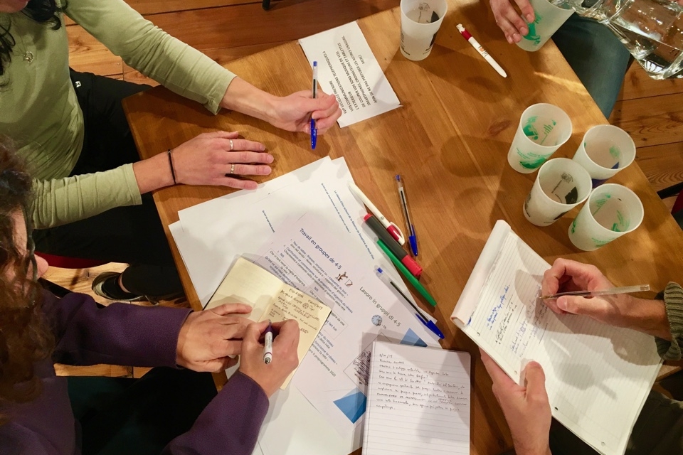 Tavola rotonda di progettazione: immagine presa dall'alto in cui si vedono mani che scrivono e fogli